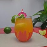 Bebida refrescante color naranja y amarillo servida con una rodaja de limón.