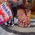 Sirviendo jugo de uva Welch's en un vaso festivo decorado con motivos de Halloween.